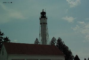 Birds fly near the lighthouse.
