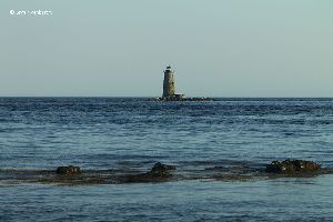 Whaleback Lighthouse with rocks in the water.